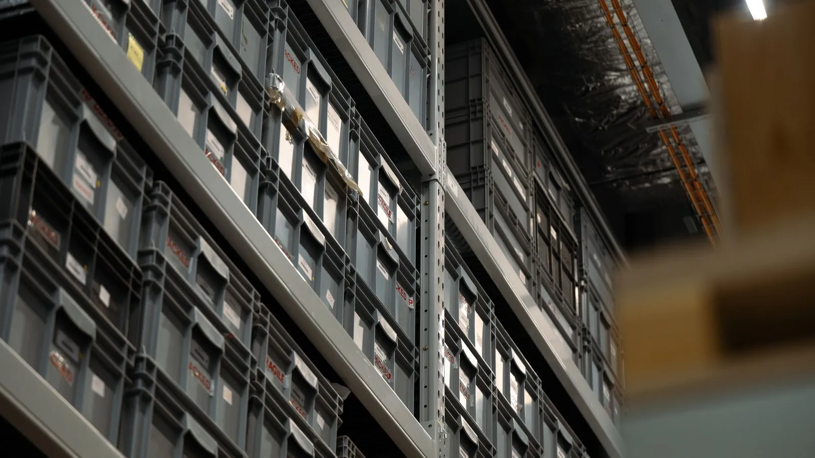 Perspective view of industrial shelves filled with organized plastic storage boxes in a warehouse.